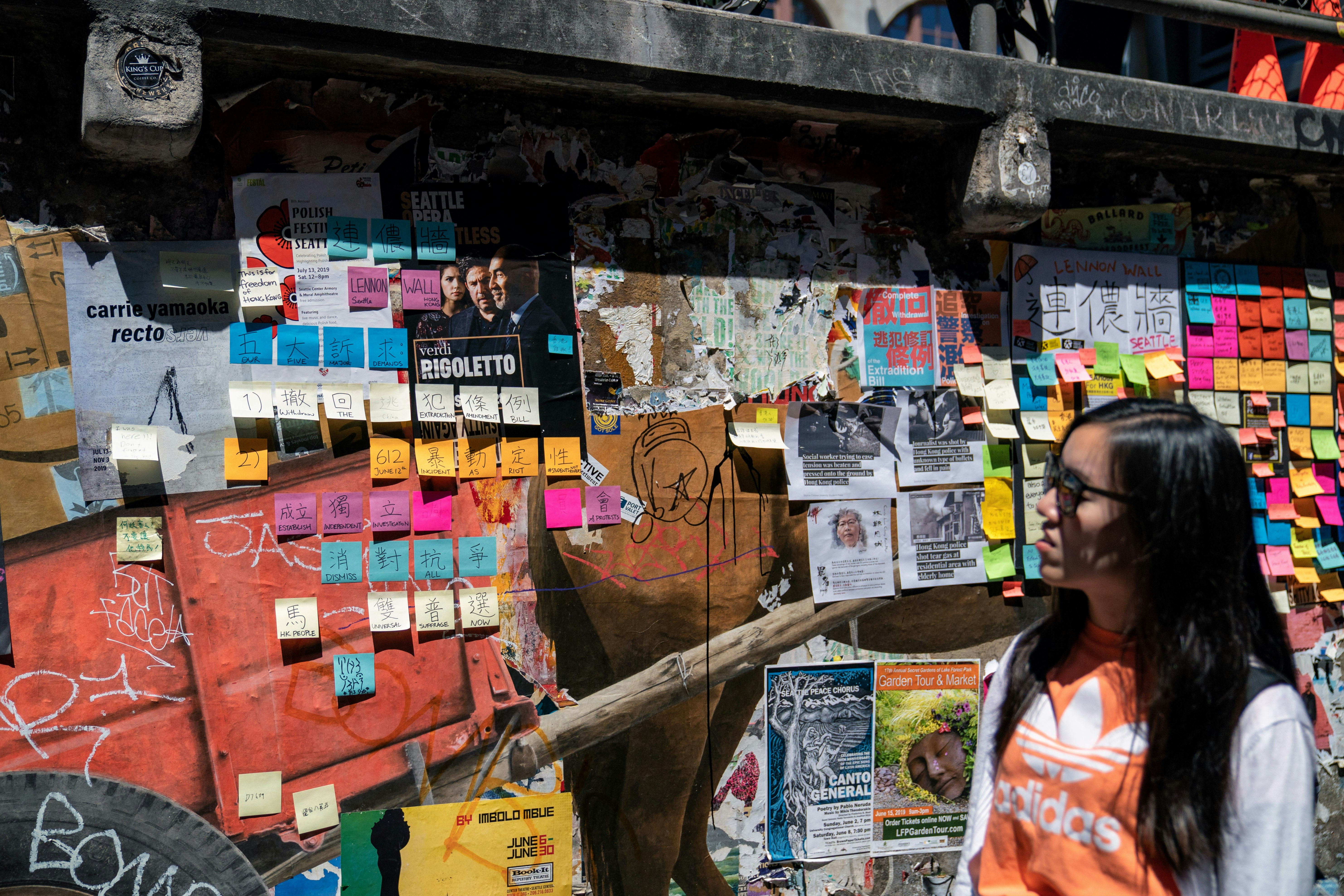 Woman looking at a wall covered in sticky notes, organizing multiple projects